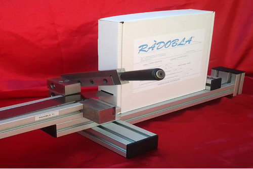 The Radobla Cutter Machine is characterised by an easily defínítíon of length thank to adiustable end stops, has a comfortable box settíng for different sÍze of box. Upon request you can also use it for the spools.<br>
				Our Cutter Machine ís buílt with light steel to guarantee strength and lightness and manageabilíty (weíght 2,5 kg) and has the option to add more piece at customer request.